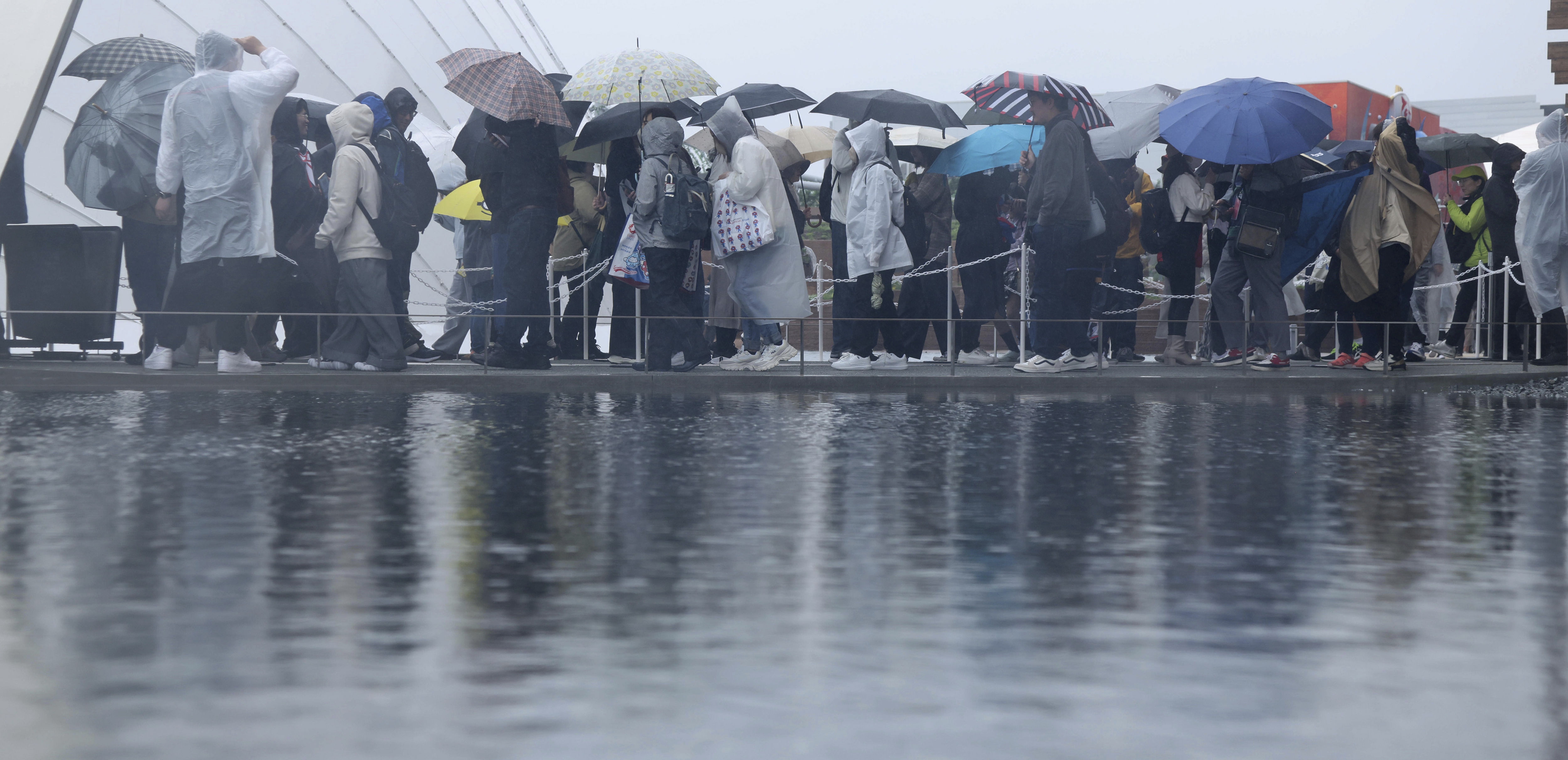 ▲▼2025大阪世博開幕13日第一天下起大雨，民眾狼狽撐傘排隊進場。（圖／達志影像／美聯社）
