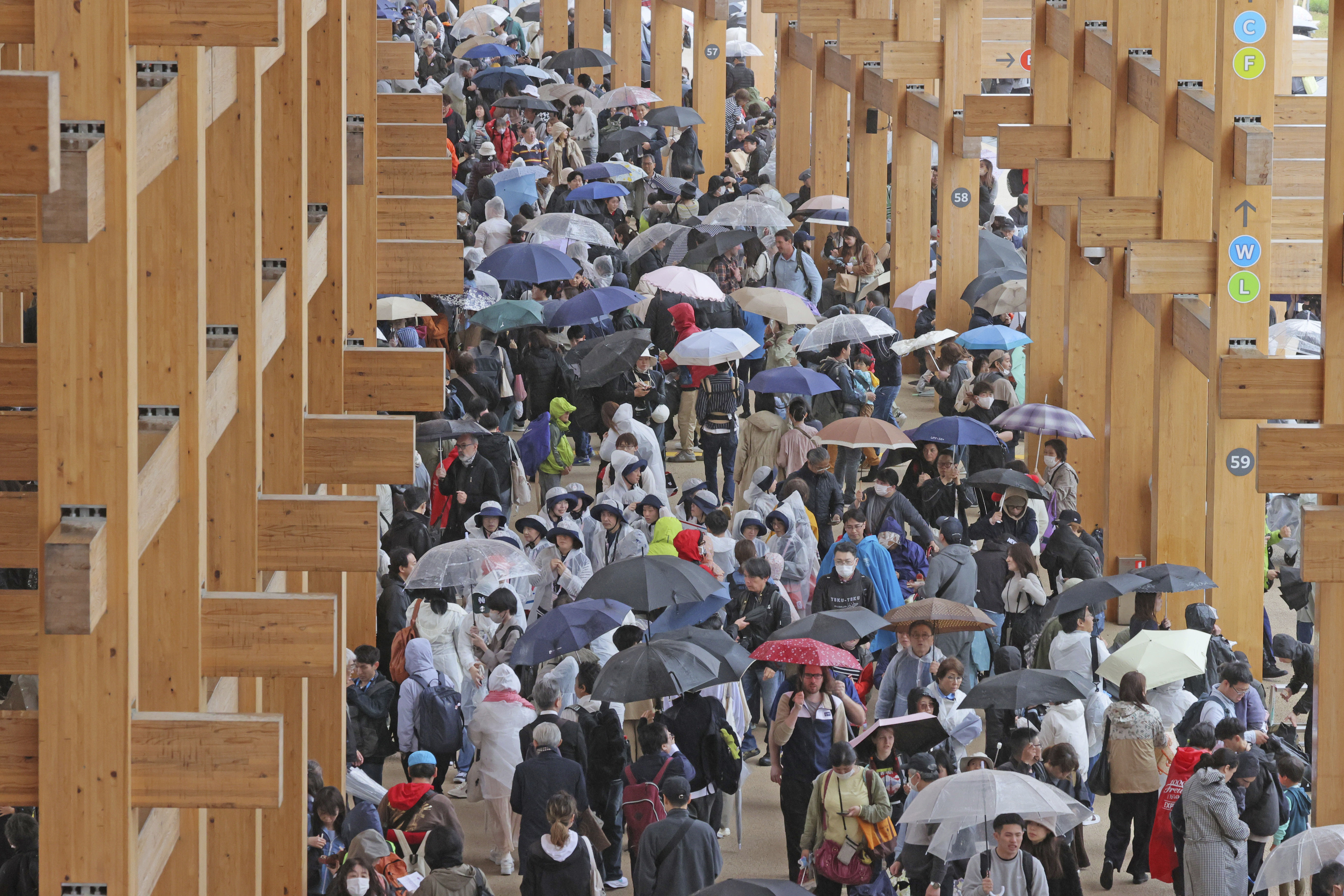 ▲▼2025大阪世博「大屋頂環」東側區域13日因大雨導致滲水，民眾持雨傘。（圖／達志影像／美聯社）