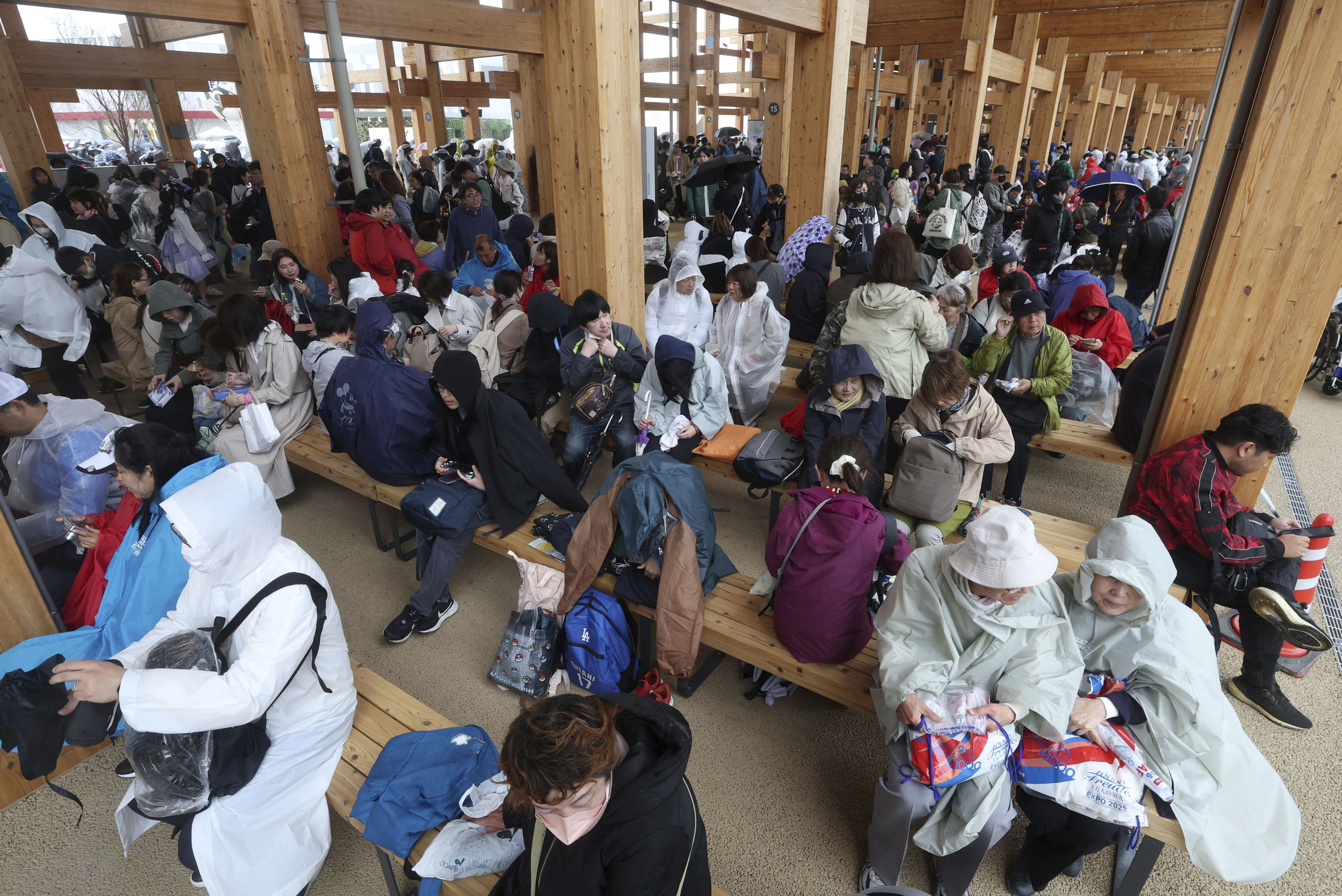 ▲▼許多民眾穿雨衣在大屋頂環廊道坐著躲雨。（圖／達志影像／美聯社）
