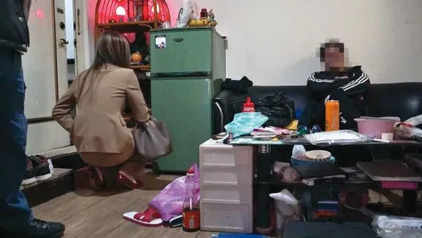 檢警去年底到張男租屋處搜索，張男（右）被要求坐在椅子上等候。（翻攝畫面）