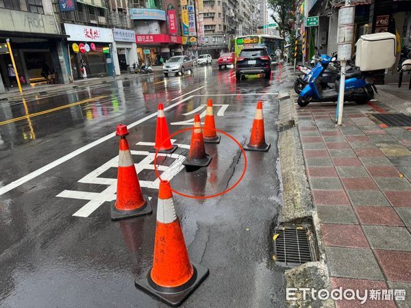 ▲▼公車行駛過停靠區時發生路面坍塌，出現一個大坑洞，新北市養工處已經用三角錐放置警示，待雨停後施工填補             。（圖／記者陳以昇翻攝）