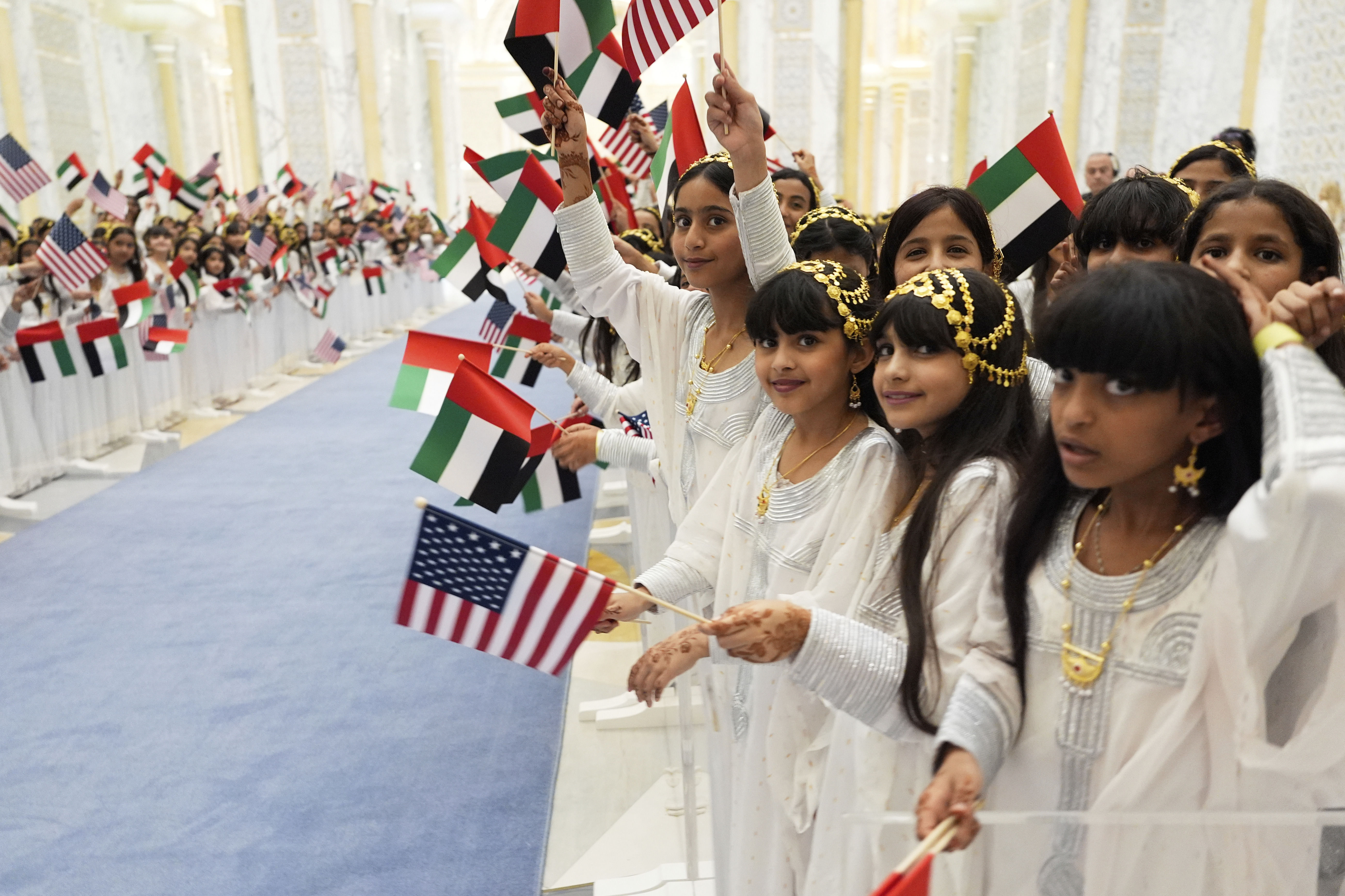 ▲▼身穿白色長袍、留著長髮的女孩們揮舞美國與阿聯酋國旗，迎接川普到來。（圖／達志影像／美聯社）
