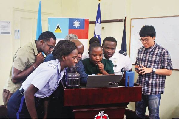 林睿庠（右）在聖露西亞擔任替代役，教導當地司法警察如何偵辦暗網毒品交易不法，詎料他竟是全球大毒梟，相當諷刺。（翻攝國發會臉書）