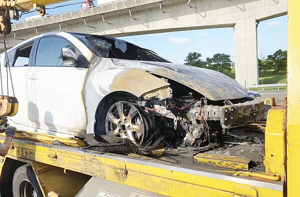 ▲國2東向大園段下午近4時許發生火燒車，警消處理後將事故轎車拖離現場，但白色馬自達轎車前半部幾乎全毀。（圖／國道一隊提供）