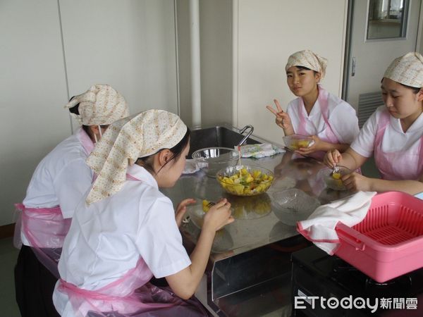 ▲日本北海道聖華高等學校學生手拿國旗開心品嘗來自台南的鳳梨，直呼「超甜超好吃」。（記者林東良翻攝，下同）