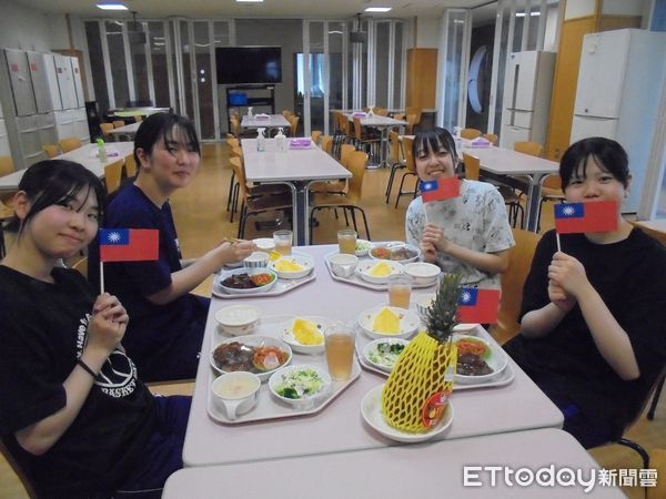 ▲日本北海道聖華高等學校學生手拿國旗開心品嘗來自台南的鳳梨，直呼「超甜超好吃」。（記者林東良翻攝，下同）