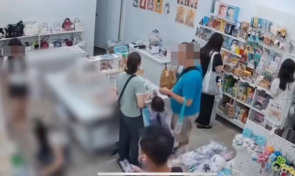 ▲▼1名身穿黑色背心的男子，趁短裙女店員蹲身找飾品，竟公然拍攝臉部和胸口，令人作噁。（圖／翻自記者爆料網）