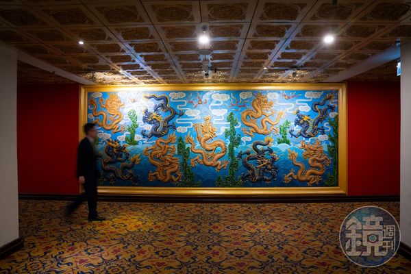 參觀密道的客人分流去地下室集合，入口的銅板浮雕九龍壁，是仿造北京故宮牆打造。