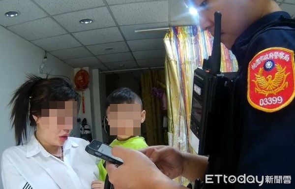 ▲員警抱著蘇小弟陪同她回家，經查證身分無誤將小朋友交還蘇太太。（圖／桃園警分局提供）