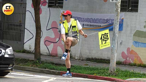 拒馬被移開後，邱彥翔開始專心指揮車輛，還不知為何忽然抓住腿。（圖／本刊攝影組）
