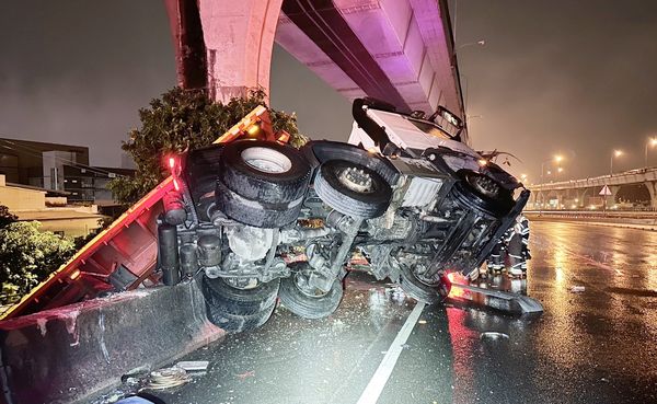 ▲國一桃園交流道入口匝道聯結車自撞護欄翻覆事故現場，聯結車車斗懸空。（圖／國道一隊提供）