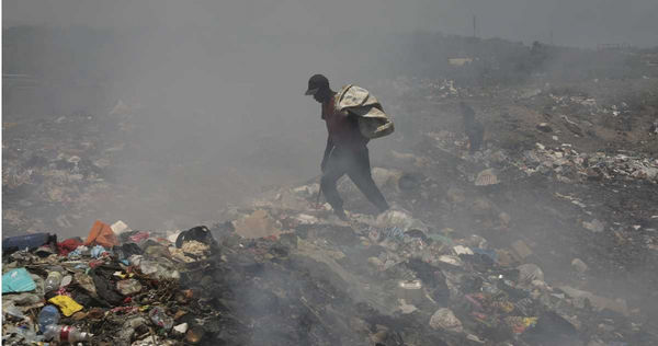 一名男子在海地太子港的垃圾掩埋場找有用的物品。