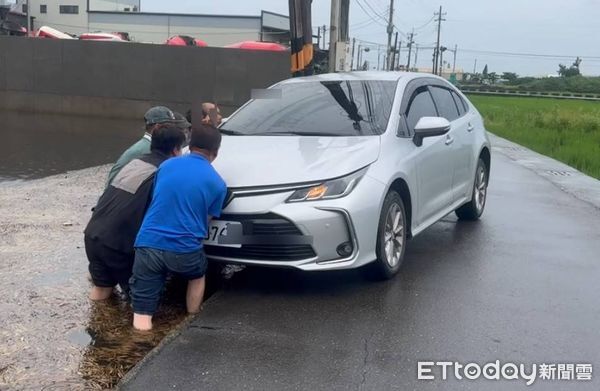 ▲彰化伸港鄉暴雨轎車卡農田，移工捲褲管下田協助脫困。（圖／賴清美提供）