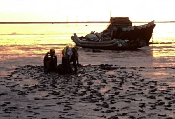 ▲遊客拍海堤夕陽深陷泥灘消防搶救。（圖／民眾提供）