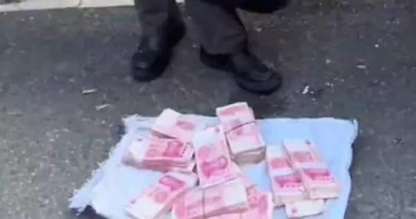 一名中年男子在菜市場附近街頭擺出大疊疑似現金，引發大量路人圍觀。（圖／翻攝自《極目新聞》）