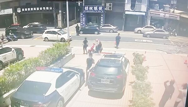 ▲桃園市新屋警分駐所旁大樓今天上午遭強風吹襲，大型玻璃被吹落地面差點砸中路過女騎士，員警將女騎士攙扶至路旁協助。（圖／楊梅警方提供）