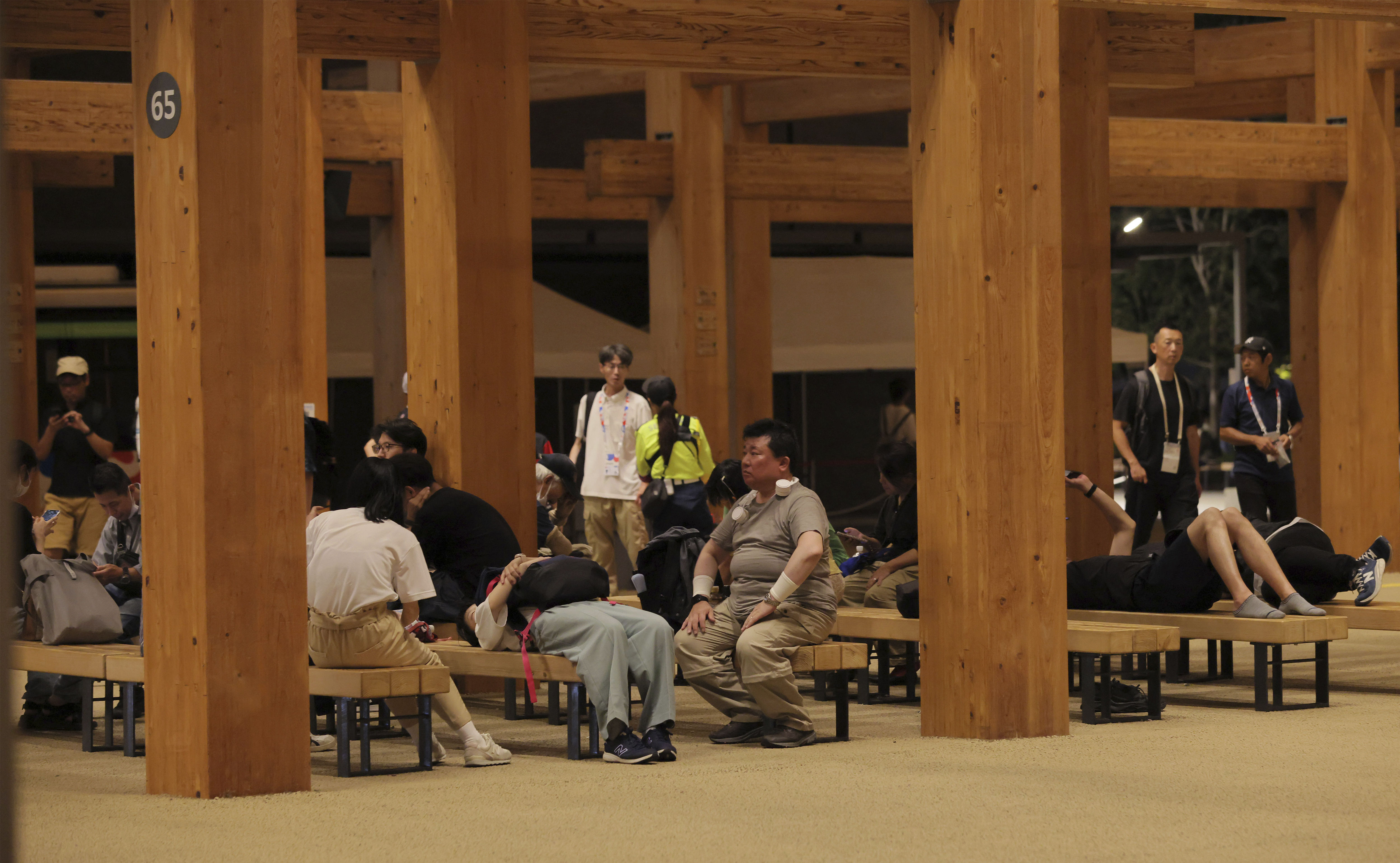 ▲▼大阪世博遊客只能躺在長椅上睡覺，或是在大屋頂環下的長椅休息。（圖／達志影像／美聯社）