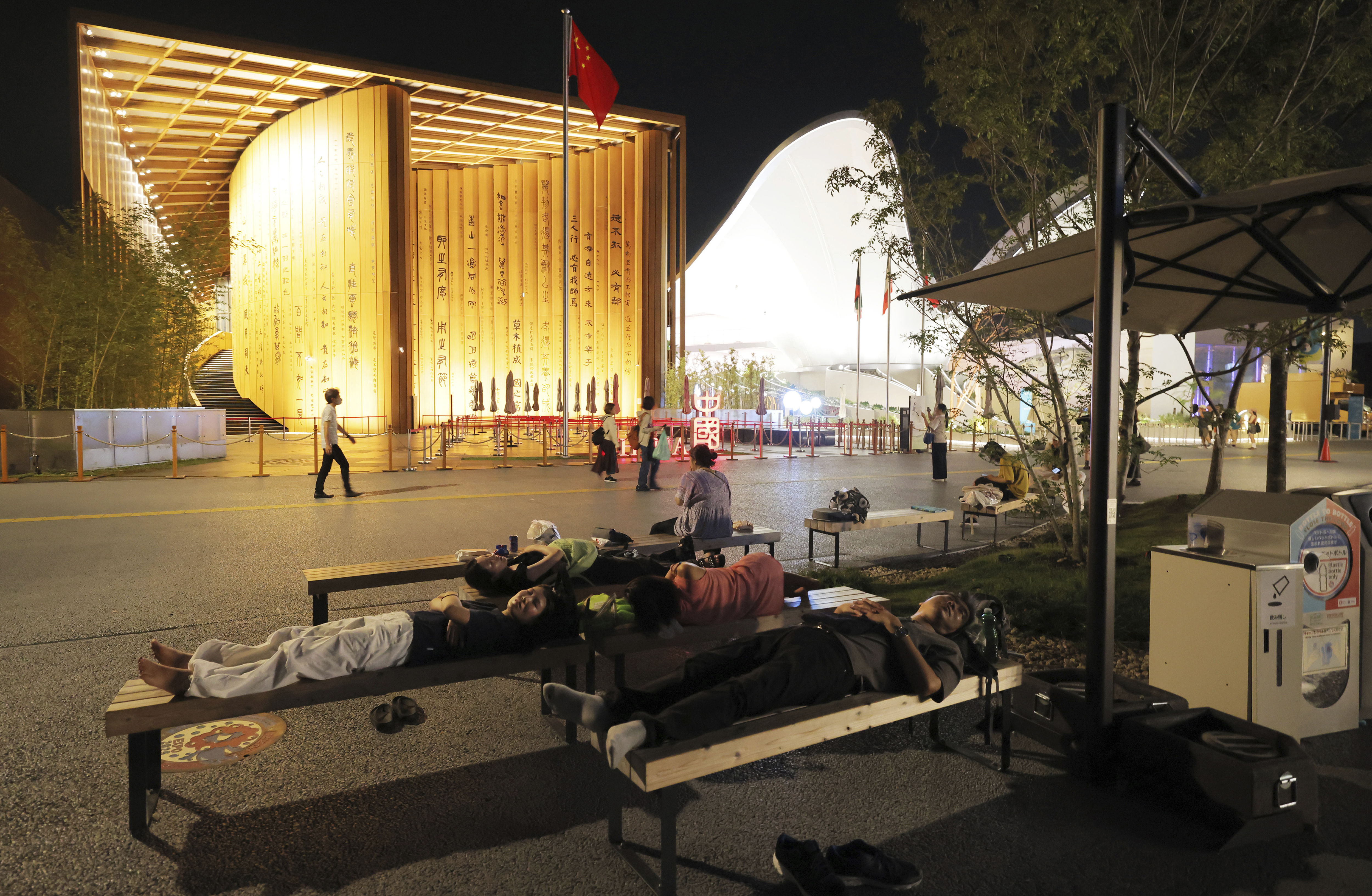 ▲▼大阪世博遊客只能躺在長椅上睡覺，或是在大屋頂環下的長椅休息。（圖／達志影像／美聯社）