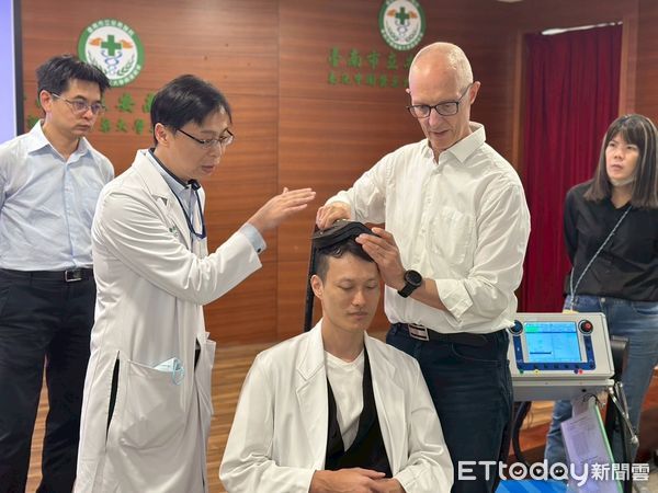▲安南醫院舉辦TMS專題演講與實作工作坊，醫學應用科學家　Dr. Claus Mathiesen（右）示範TMS（重複經顱磁刺激）治療定位與操作技巧，與精神科張俊鴻主任（左二）進行臨床交流。（記者林東良翻攝，下同）