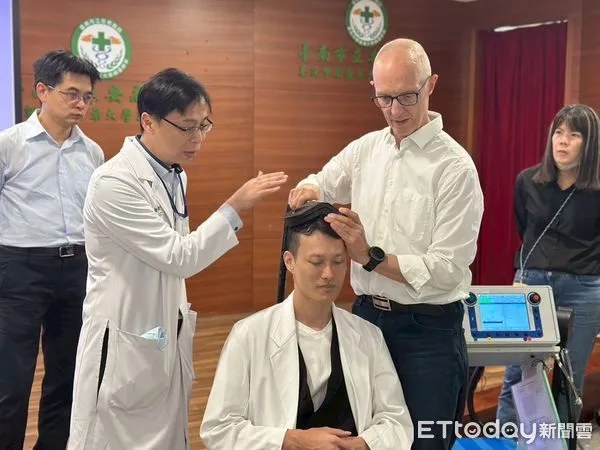 ▲安南醫院舉辦TMS專題演講與實作工作坊，醫學應用科學家　Dr. Claus Mathiesen（右）示範TMS（重複經顱磁刺激）治療定位與操作技巧，與精神科張俊鴻主任（左二）進行臨床交流。（記者林東良翻攝，下同）