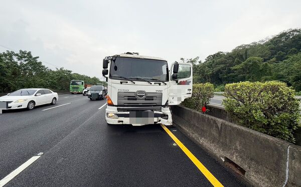 ▲一輛大貨車昨天下午行經國道3號大溪北向路段時，左前輪爆胎失控撞擊內側寶馬轎車，隨即停靠內側。（圖／國道六隊提供）