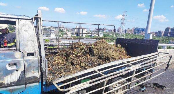 ▲國道1號高架南向桃園段今天上午發生小貨車火燒車事故，桃園市消防局青埔分隊撲滅火勢後檢視車斗處堆滿樹枝與落葉等雜物。（圖／國道一隊提供）