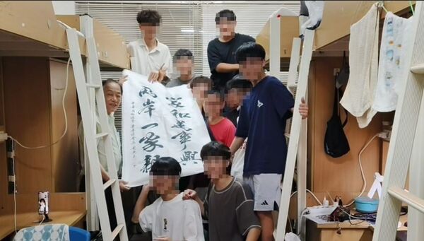 文化大學宿舍大合照中，69歲博士阿伯舉著「兩岸一家親」書法，畫面在網路瘋傳。（翻攝自Threads）
