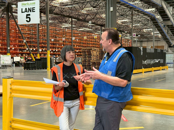 ▲資深媒體人范琪斐（左）到美國iHerb總部體驗倉庫繁忙的物流工作。（圖／iHerb提供）