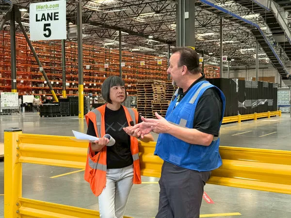 ▲資深媒體人范琪斐（左）到美國iHerb總部體驗倉庫繁忙的物流工作。（圖／iHerb提供）