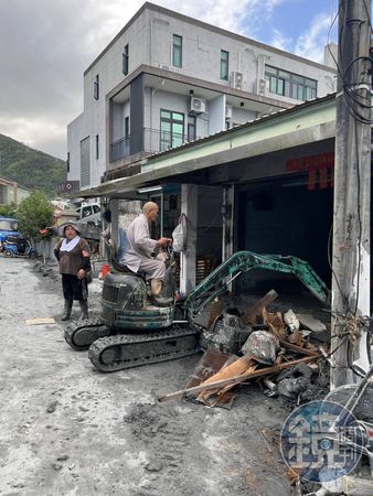 在敦厚路上，一名套上雨鞋、開著怪手的出家人正在幫災民清運汙泥雜物。