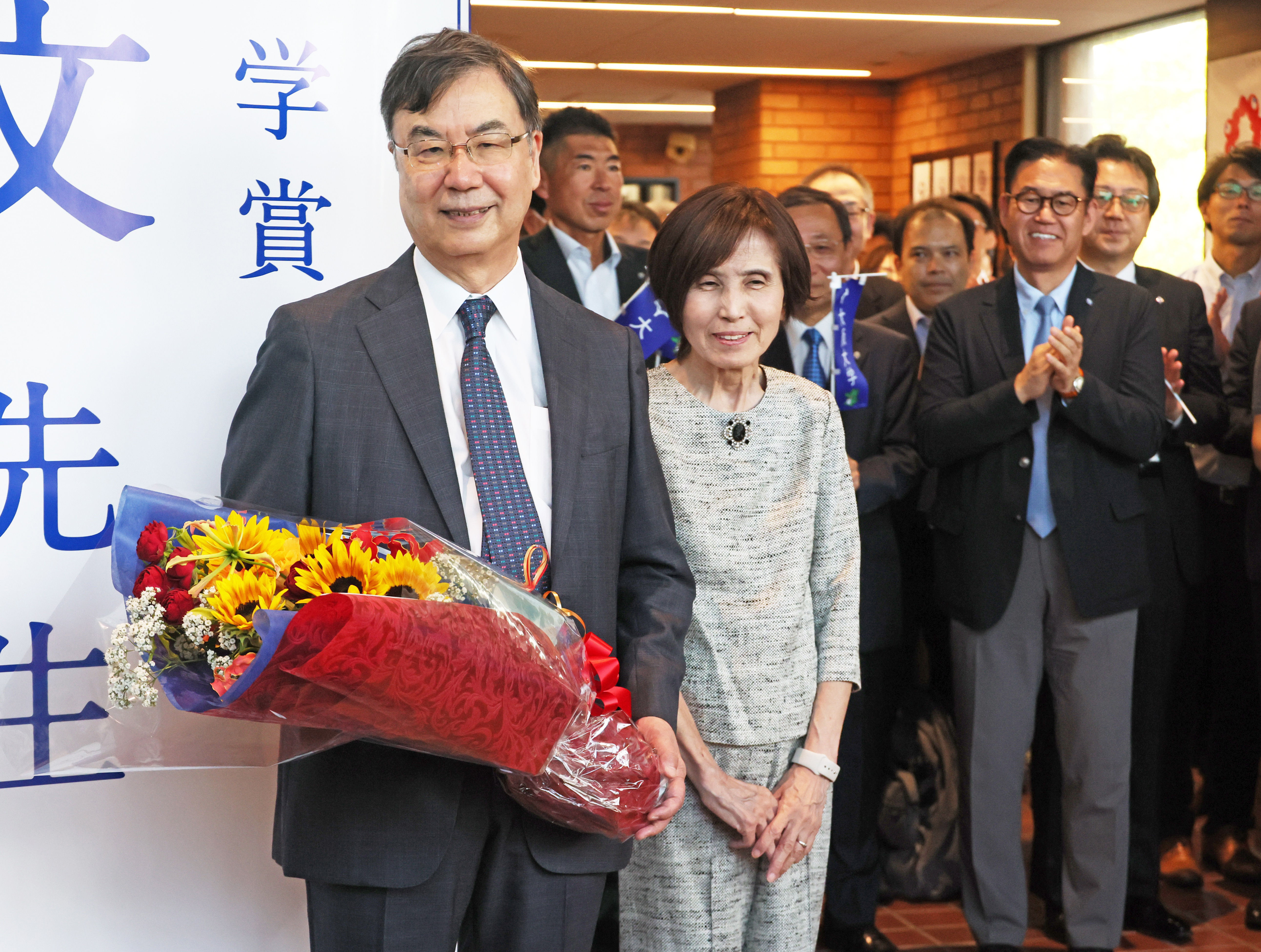 ▲▼日本免疫學者坂口志文與其妻子教子7日上午抵達大阪大學,收下花束。(圖/達志影像/美聯社)