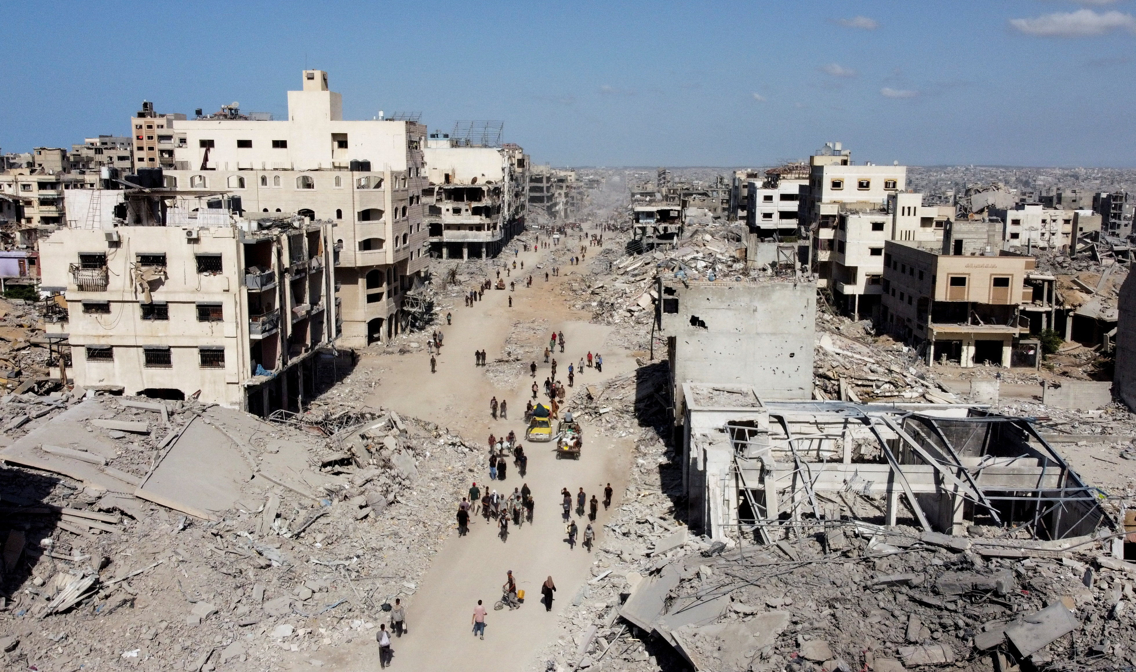 ▲▼ 加薩停火協議生效，以軍撤出後的空拍畫面可見巴勒斯坦人走過廢墟。（圖／路透）