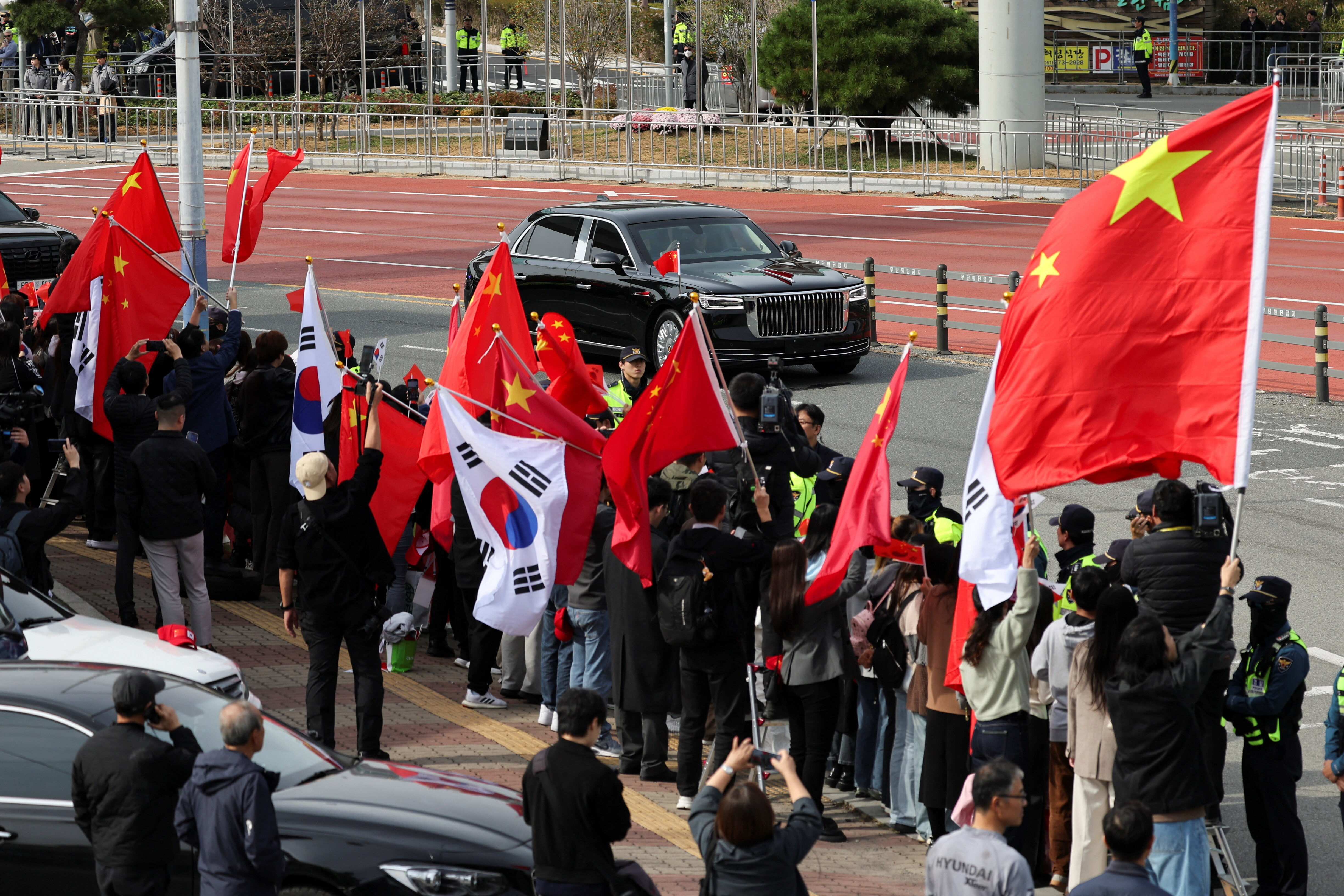 ▲▼習近平車隊駛離金海國際機場，街道群眾揮舞中國國旗歡送。（圖／路透）