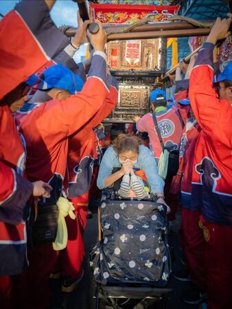 ▲北港媽神轎20日進入府城鬧區，轎班特地抬高神轎，破例讓王媽媽與兒子推車鑽轎。（朝天宮攝影組提供）