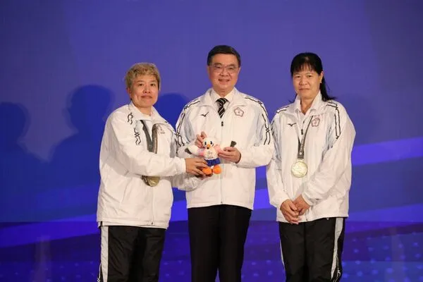 ▲2025年東京第25屆達福林匹克運動會返國餐會，由保齡球女子團體賽金牌選手張堯茜(左)、王玉琴(右)致贈大會吉祥物予行政院卓榮泰院長(中)。（圖／運動部提供）