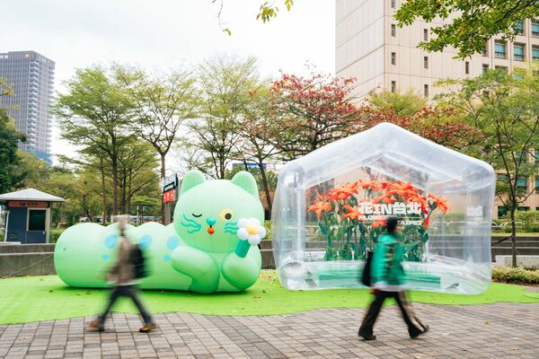 ▲「喵喵」氣偶於台北市政府東南角廣場首亮相，一旁設置透明的「春之幻境溫室」和百合紙藝，將展至3月1日。（圖／公園處提供）