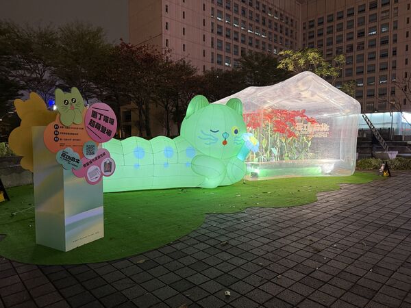 ▲「喵喵」氣偶於台北市政府東南角廣場首亮相，一旁設置透明的「春之幻境溫室」和百合紙藝，將展至3月1日。（圖／公園處提供）