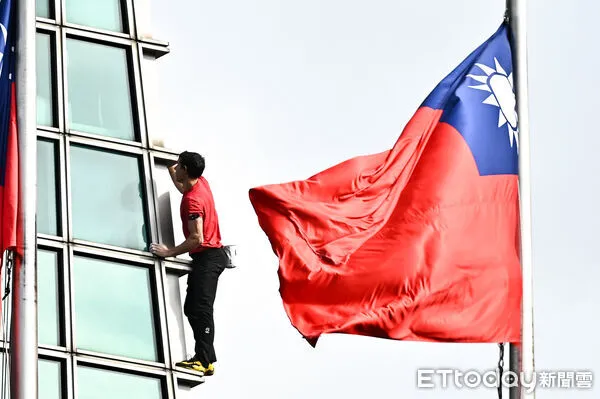 ▲▼美國自由攀岩名將霍諾德（Alex Honnold）於台灣時間25日挑戰徒手攀登台北101，攀爬時剛好與101大樓前懸掛的國旗相互映襯。（圖／記者李毓康攝）