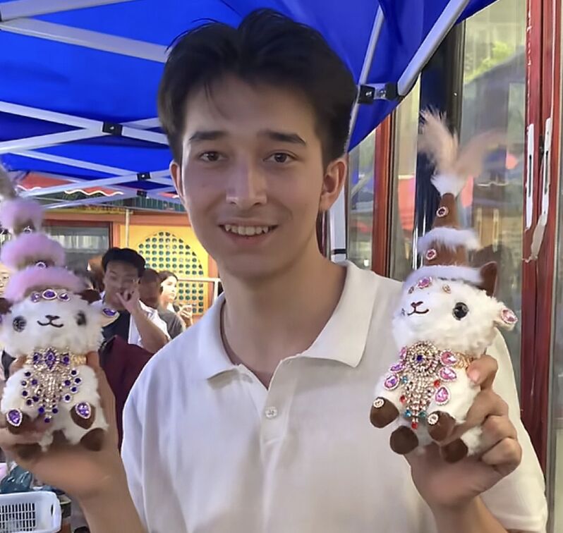 ▲帥哥老闆阿卜杜拉和他手工製作的「新疆小羊」布偶。（圖／翻攝極目新聞）