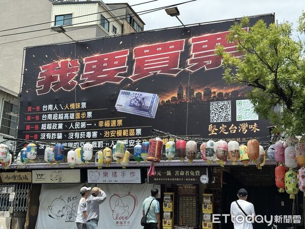 ▲台南街頭出現寫著「我要買票」的大型看板，搭配千元鈔票圖像，引發路人側目及討論。（記者林東良翻攝）